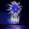 Holiday fireworks silver and blue colors over the sea with reflection