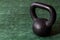 Holiday fitness, black kettle bell on a multi-shade green background with white sparkles