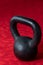 Holiday fitness, black kettle bell on a multi-shade red background