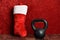 Holiday fitness, black kettlebell, red and white plush Christmas stocking against a red background