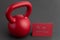 Holiday fitness, red kettlebell, with a red valentine card, on a black gym floor