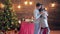 Holiday, guy hugs girl at home on background of illuminated Christmas tree with garlands