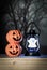 Holiday halloween with two toys pumpkin, toy lantern ghost on wooden table, vertical horror background and voodoo tone.