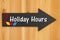 Holiday Hours type message on hanging arrow chalkboard sign with a candy cane and lights