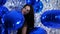 Holiday of lady with sincere smile among inflatable balloons on background of brilliant wall decorated with foil