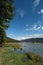 Holiday landscape surrounded by mountains, trees, river and reed.