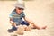 Holiday, little boy three years old fun digging in the sand at the beach