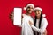Holiday Offer. Cheerful Middle Eastern Couple In Santa Hats Demonstrating Blank Smartphone