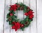 Holiday Poinsettia Christmas wreath on rustic white wooden board