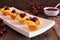 Holiday puff pastry appetizers with cranberries and baked brie, side view serving plate against rustic wood