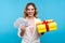 Holiday sales. Portrait of happy joyous woman smiling genuinely and holding bunch of dollars and wrapped present box. blue