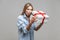 Holiday surprise. Portrait of astonished curious woman in denim shirt looking inside gift box. studio shot isolated on gray