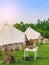 Holiday tents and lounge areas on green lawn place among trees at natural parkland. Camping tent on nature in summer.Travel