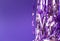 Holiday tinsel on violet background, horizontal. Creative backdrop