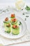 Holiday vegetable appetizers. Cucumbers rolls with soft cheese, pieces of salted salmon, microgreens and black sesame served on a