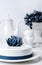 Holiday white mousse cake decorated with blue creative flower with tea set and grape on stand cake on background. Vertical Food