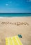 Holiday written on the beach with towel and flip flops over sea