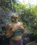 Holidays adventure lifestyle portrait - young beautiful and happy woman taking natural shower from waterfall in the jungle