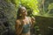 Holidays adventure lifestyle portrait - young beautiful and happy woman taking natural shower from waterfall in the jungle