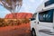 Holidays in Australia. White motorhome without logos, parked facing Mount Uluru. Medium size caravan, place for two people with