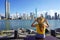 Holidays in Balneario Camboriu, Brazil. Rear view of young woman in hat relaxing sitting on bench enjoy skyline of Balneario