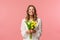 Holidays, beauty and spring concept. Portrait of happy excited charming blond girl receive flowers, buying yellow tulips