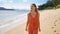 Holidays in Brazil. Panoramic banner of young traveler woman in orange sundress walking relaxed on sand in tropical beach of