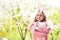 Holidays celebration concept Easter and spring. Happy girl holding pink rabbit in garden with blossoming trees.