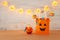 Holidays image of Halloween. Pumpkins, bats, treats, paper gift bag over wooden table