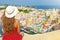 Holidays in Italy. Back view of beautiful girl with hat on wall looking at stunning sight of Procida Island, Naples, Italy