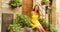 Holidays in Italy. Happy cheerful young woman sitting on steps house beween colorful flowers and plants in Assisi small medieval