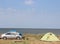 Holidays at sea with a tent, family camp on the shore of the Sea with a car, a wooden table and a bench