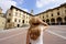 Holidays in Tuscany. Rear view of traveler girl holds hat in Piazza Grande square in the old town of Arezzo, Tuscany, Italy