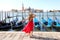 Holidays in Venice. Back view of beautiful girl in red dress enjoying view of Venice Lagoon with the island of San Giorgio