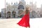Holidays in Venice. Back view of pretty girl in elegant red dress dancing in St Mark`s Square in Venice, Italy. Beautiful young