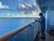 The Holland America Line Zuiderdam cruise ship maintenance crewman sanding and painting the railing