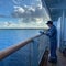 The Holland America Line Zuiderdam cruise ship maintenance crewman sanding and painting the railing