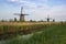 Holland - Kinderdijk, open-air museum of windmills. Three mills standing in tall grass, in front of mills a water channel