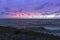 Holland - Sunset over the stormy sea. A stone rampart jutting out into the sea. in the foreground sand and green grass