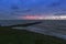 Holland - Sunset over the stormy sea. A stone rampart jutting out into the sea. in the foreground sand and green grass