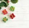 Holly Leaves and little gifts on white wooden background