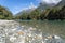 Hollyford River flowing between mountains over flat wide stony riverbed