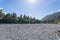 Hollyford River flowing between mountains over flat wide stony riverbed