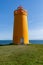 Holmsberg Lighthouse, an orange light house on the Reykjanes Peninsula in Iceland