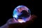 Holographic globe held by hand on dark background