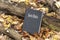 Holy Bible. Closed Bible resting on a tree trunk, on top of fallen autumn leaves