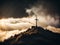 Holy cross symbolizing the death and resurrection of Jesus Christ with The sky over Golgotha Hill is shrouded in light and clouds