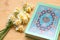 Holy Quran and daffodils bouquet on wooden background