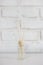 Home aroma fragrance diffuser with bamboo sticks over white brick wall