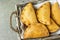 Home Baked Empanadas Turnover Pies with Pisto Vegetable Cheese Filling in Tomato Sauce in Wicker Basket. Spanish Pastry Dark Table